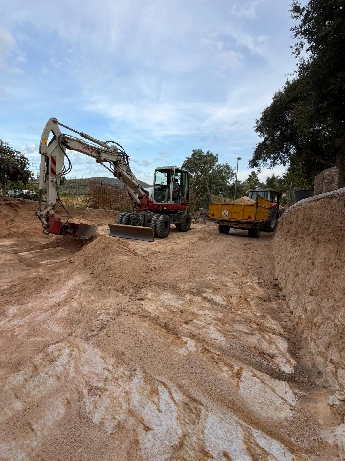 Excavadora giratòria i tractor amb remolc en una feina de moviment de terres